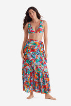 Woman wearing a multicolored bikini top with a multicolored floral wrap skirt