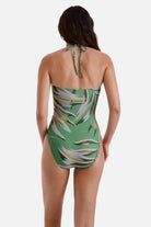 Woman turned away wearing a multicolored leaf printed one-piece swimsuit with a halter tie