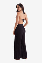 Woman turned left wearing a black bikini top and black beach pants
