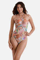 Woman wearing a tie dye one-piece swimsuit with a halter tie